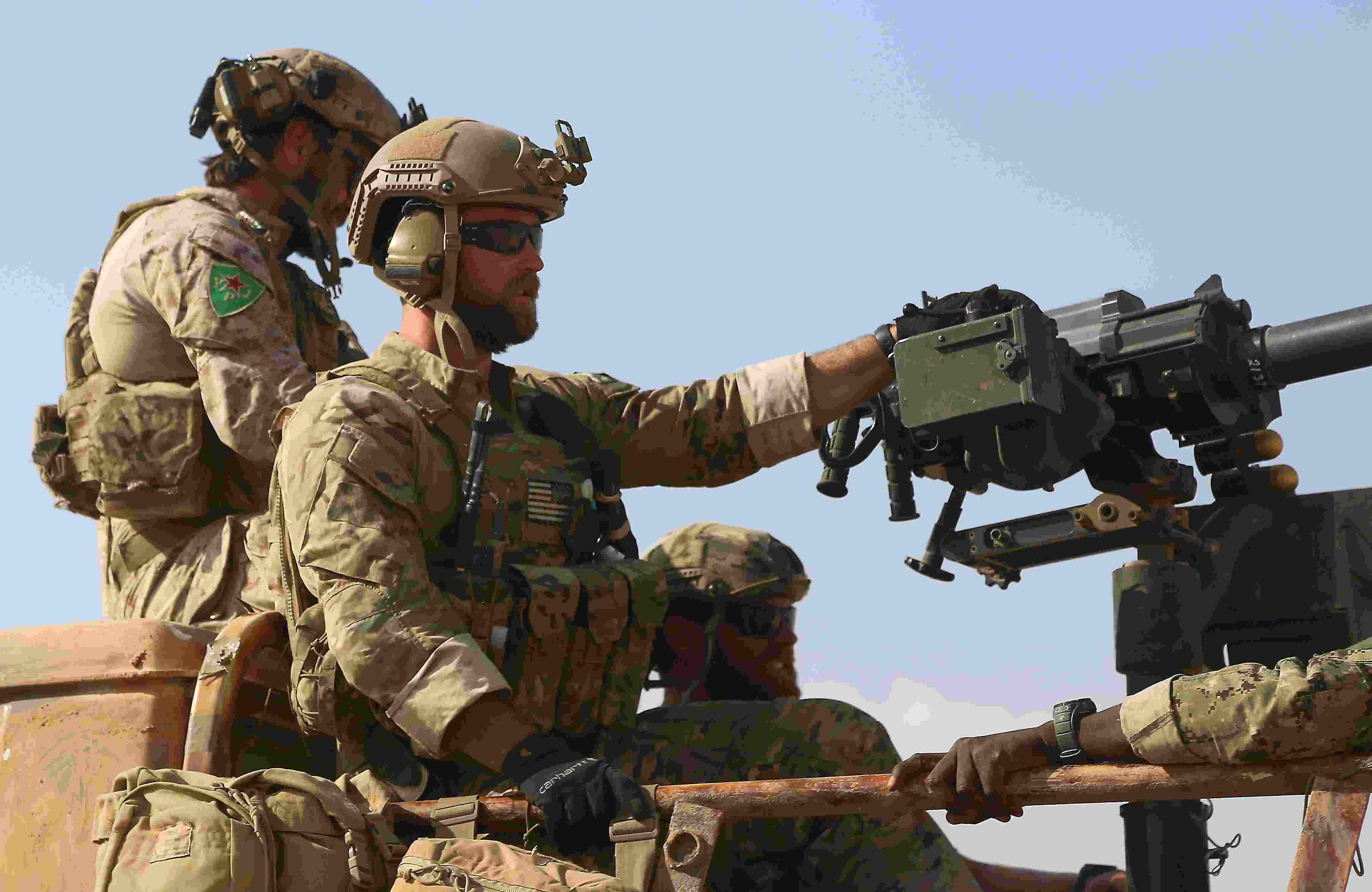 Armed men in uniform identified by Syrian Democratic forces as US special operations forces ride in the back of a pickup truck in the village of Fatisah in the northern Syrian province of Raqa on May 25, 2016. US-backed Syrian fighters and Iraqi forces pressed twin assaults against the Islamic State group, in two of the most important ground offensives yet against the jihadists. The Syrian Democratic Forces (SDF), formed in October 2015, announced on May 24 its push for IS territory north of Raqa city, which is around 90 kilometres (55 miles) south of the Syrian-Turkish border and home to an estimated 300,000 people. The SDF is dominated by the Kurdish People's Protection Units (YPG) -- largely considered the most effective independent anti-IS force on the ground in Syria -- but it also includes Arab Muslim and Christian fighters. / AFP / DELIL SOULEIMAN (Photo credit should read DELIL SOULEIMAN/AFP/Getty Images)